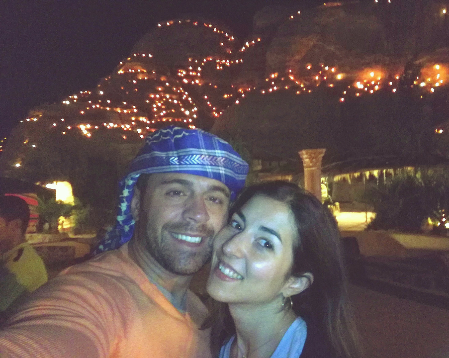 Couple posing with a lit up mountain at night.