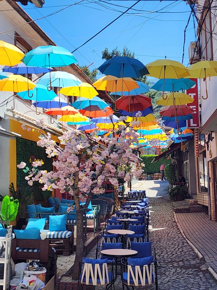 Colorful umbrellas hanging above a cobblestone street.