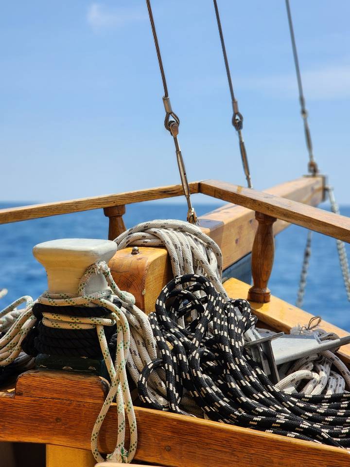 Boat deck with ropes and hardware under a clear sky.