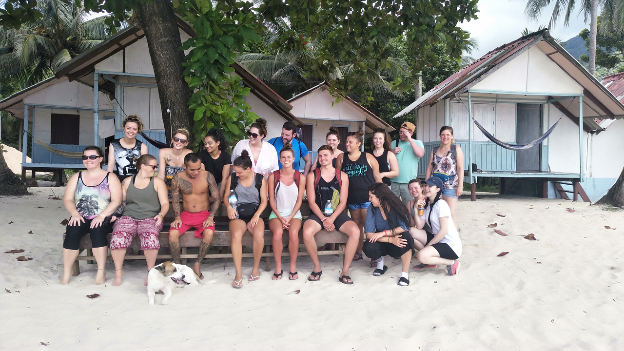 Group of people sitting on the beach by huts.