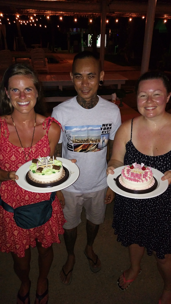 Three people showing cakes in an indoor setting.