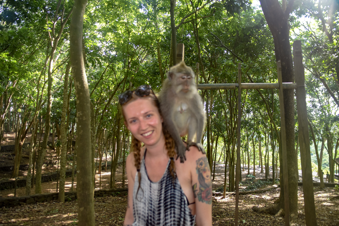Woman with a monkey on her shoulder in a forest.