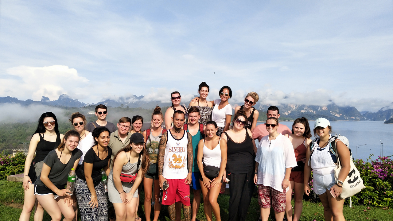 Group of people posing with a scenic mountain view.