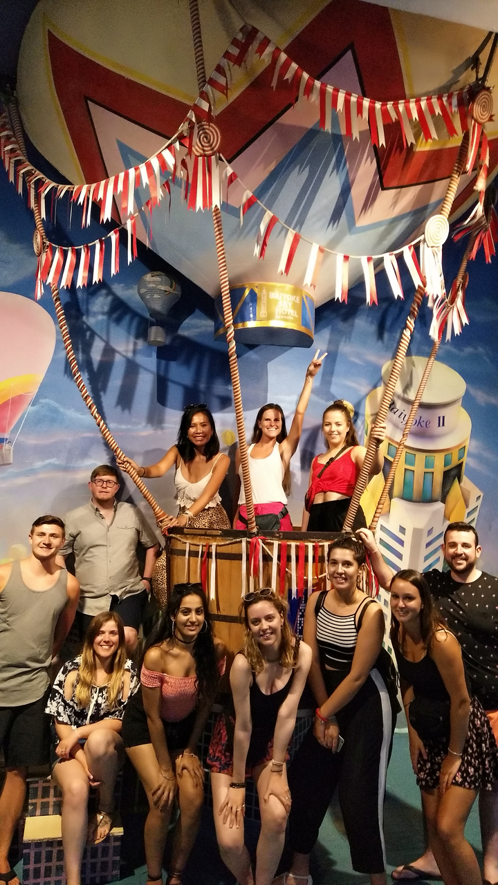 Group of people posing in a hot air balloon-themed backdrop.