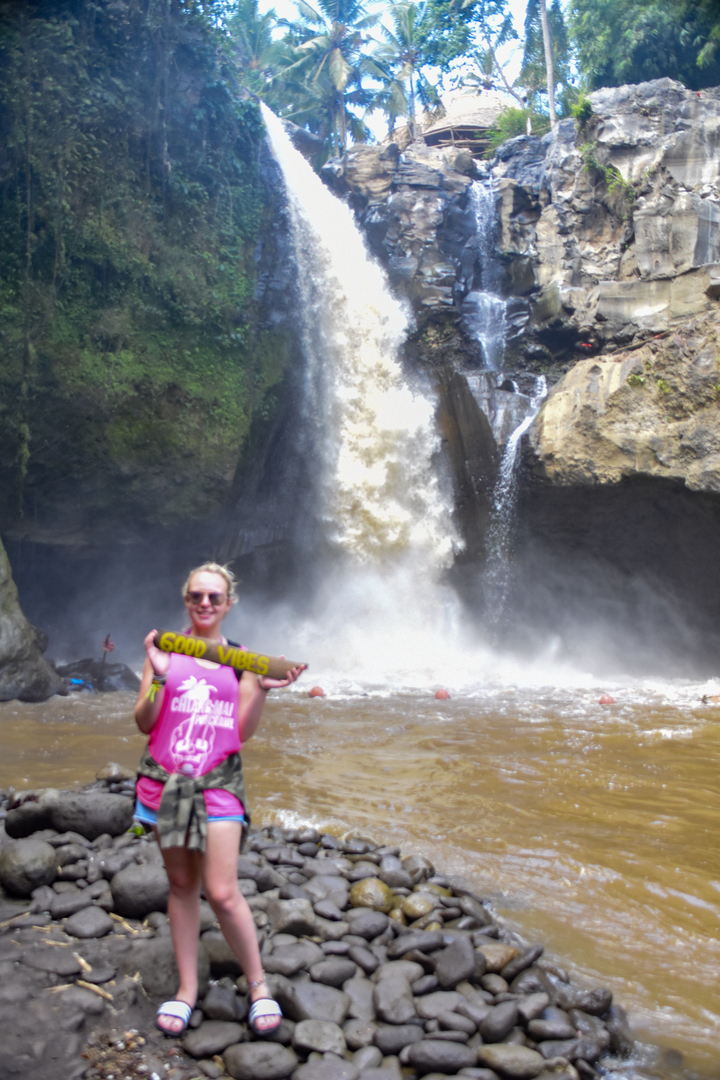 Person holding a sign in front of a waterfall, image is blurry.