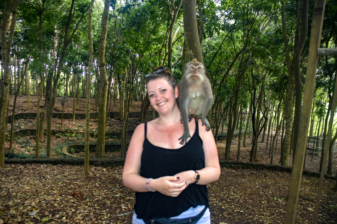 Person with a monkey on shoulder in a forest.