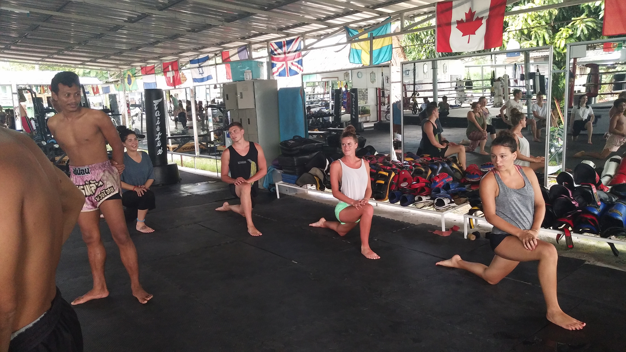 Group doing stretching exercises in a martial arts gym.