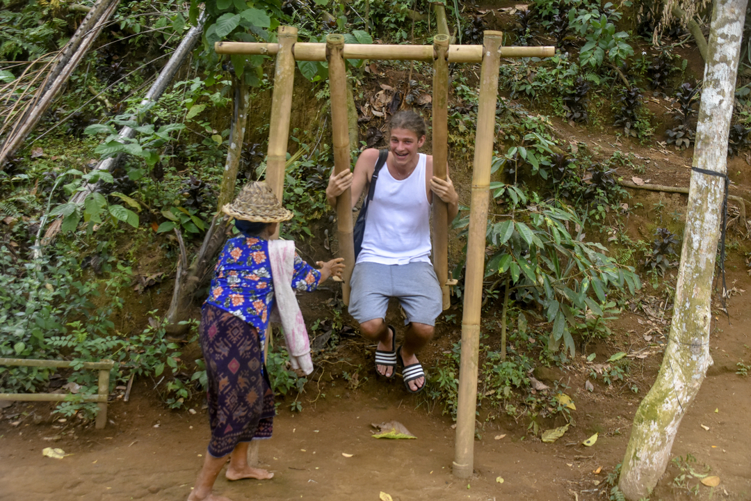 Man enjoying a swing push in a rustic setting.