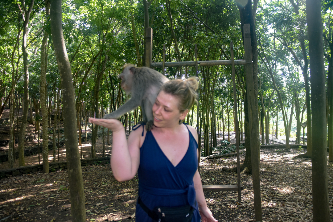 Woman with a monkey in a forest setting.
