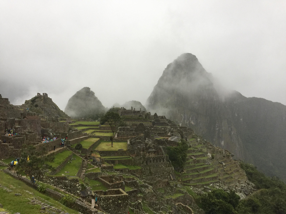 Vue brumeuse du Machu Picchu avec d'anciennes terrasses et des montagnes.