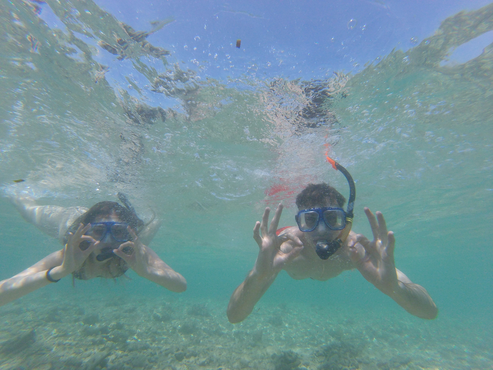 Snorkelers underwater showing hand signs.