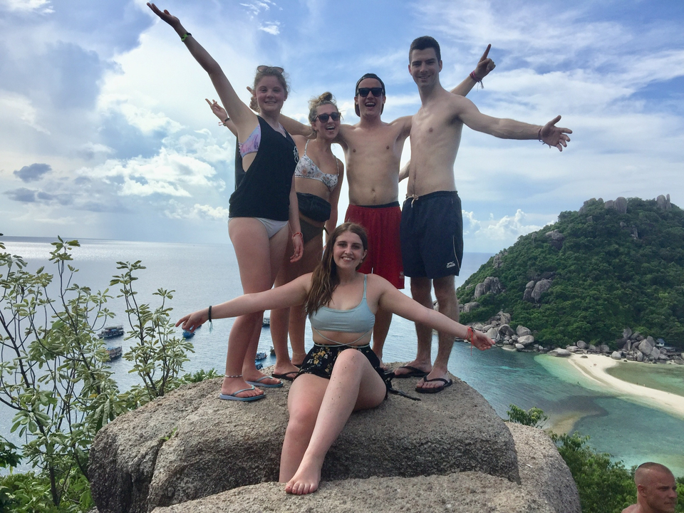 Group posing on a rock with ocean view.