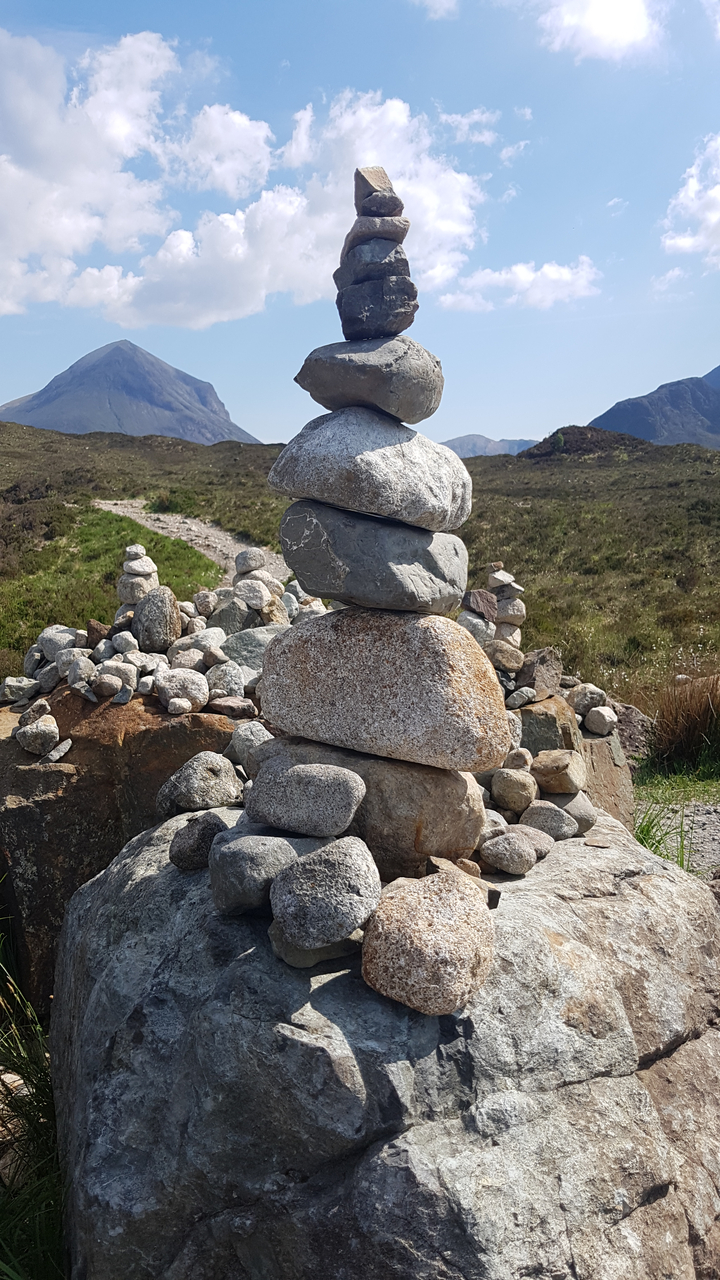 Stack of balanced stones in the foreground with path leading away.