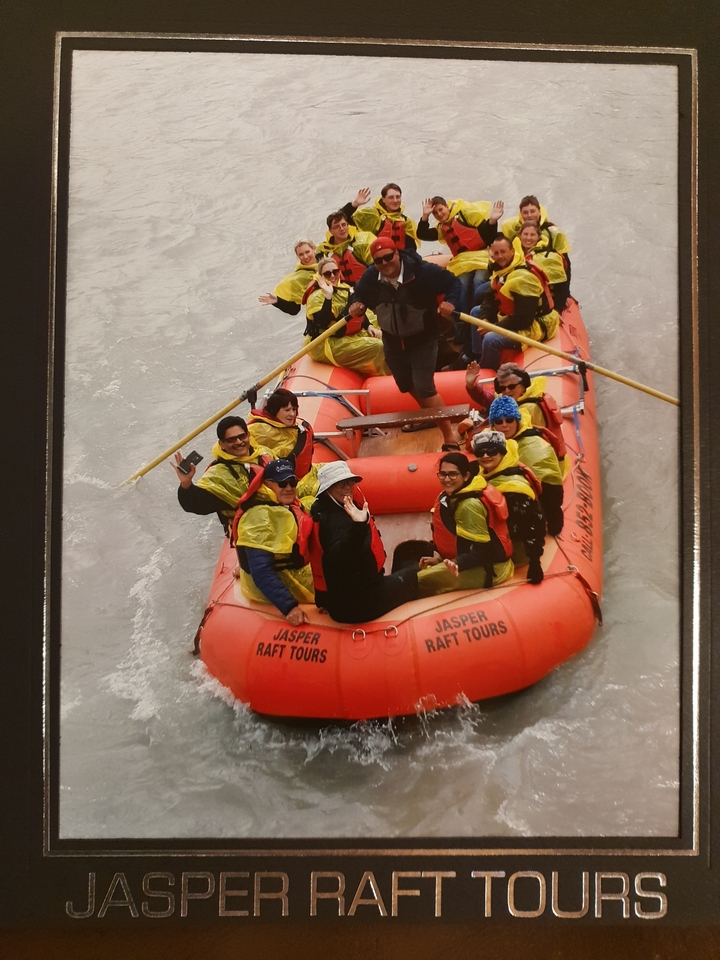 Groupe de personnes dans un radeau sur une rivière, portant des gilets de sauvetage.