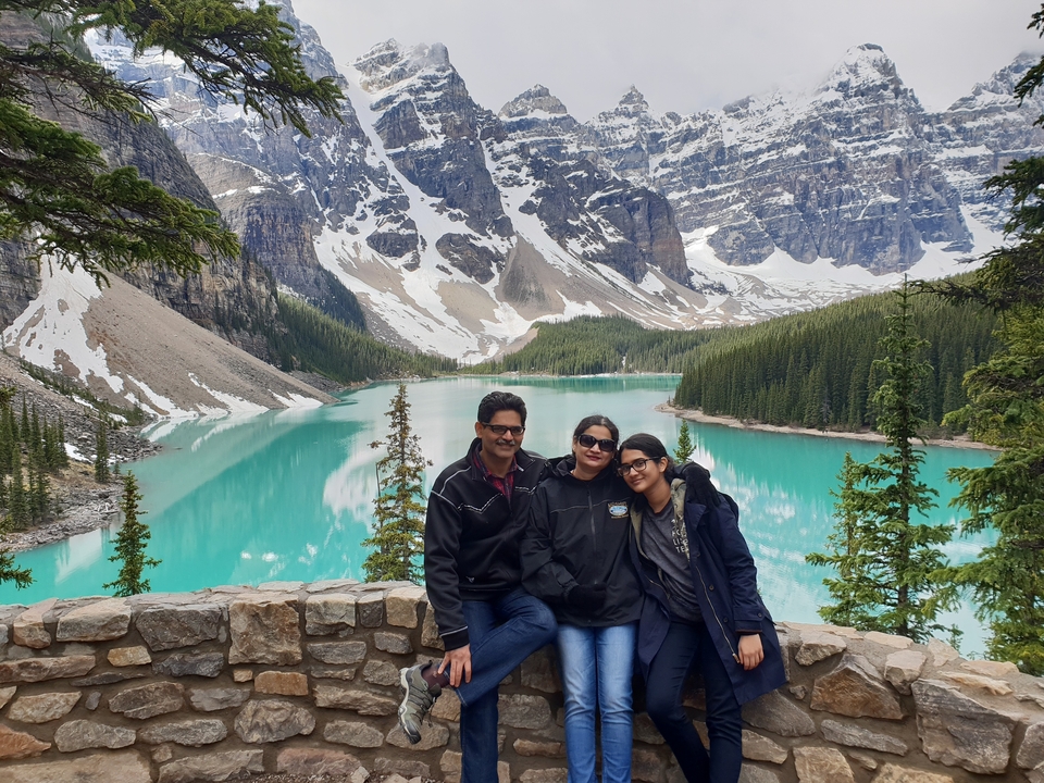 Famille posant avec un magnifique lac bleu et des montagnes en arrière-plan.