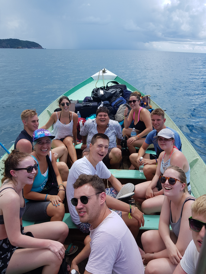 Group of people on a longtail boat enjoying a trip on the water.