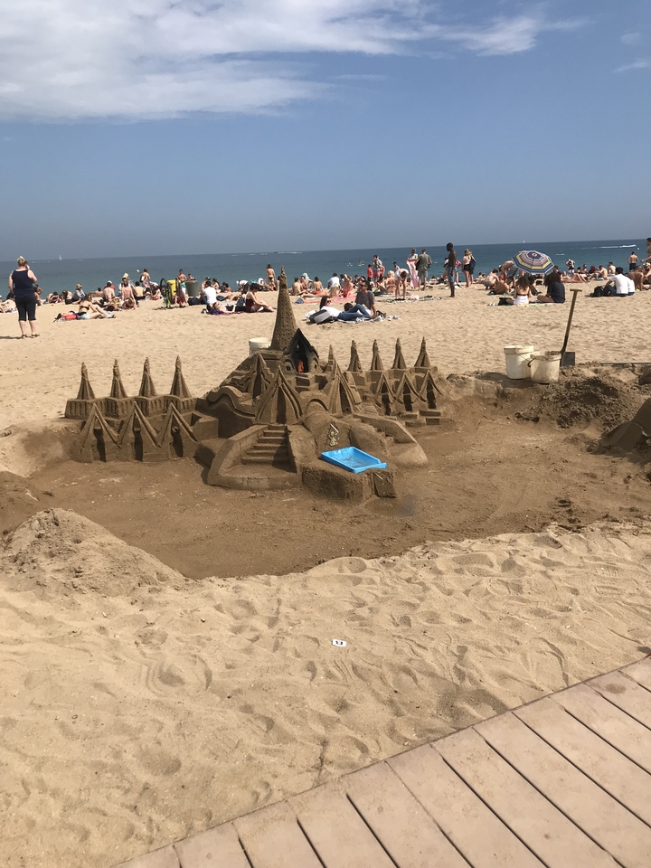 A sand sculpture on a crowded beach.