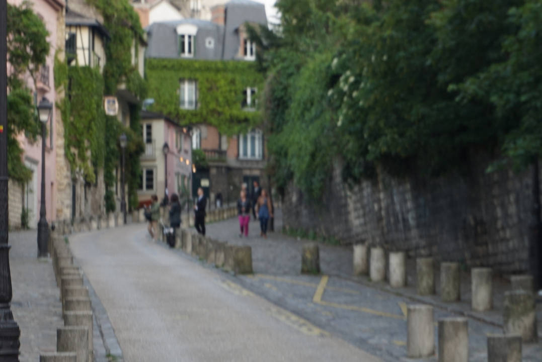 Vue floue d'une rue avec des personnes marchant le long d'un chemin pavé.