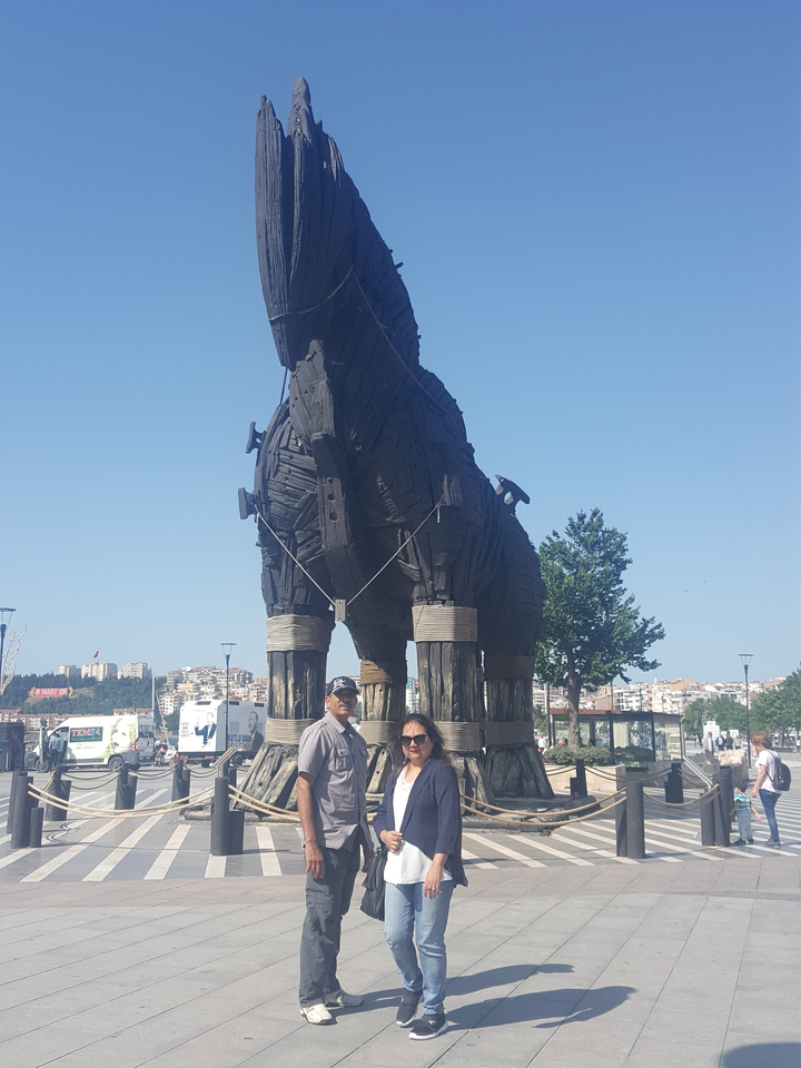 A couple standing in front of the Troy Horse statue.