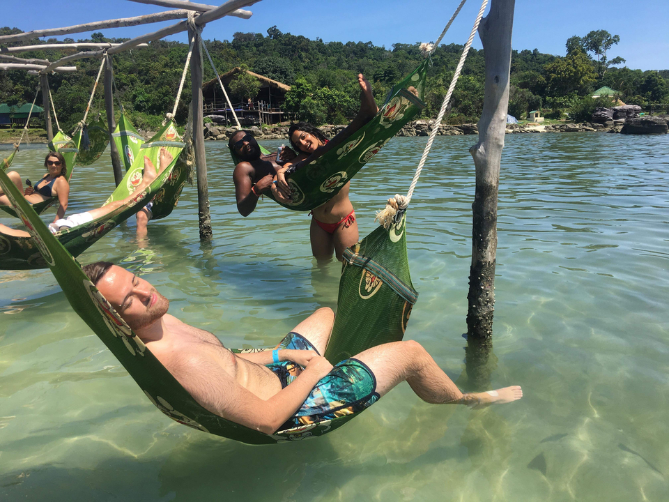 People relaxing in hammocks over the water.