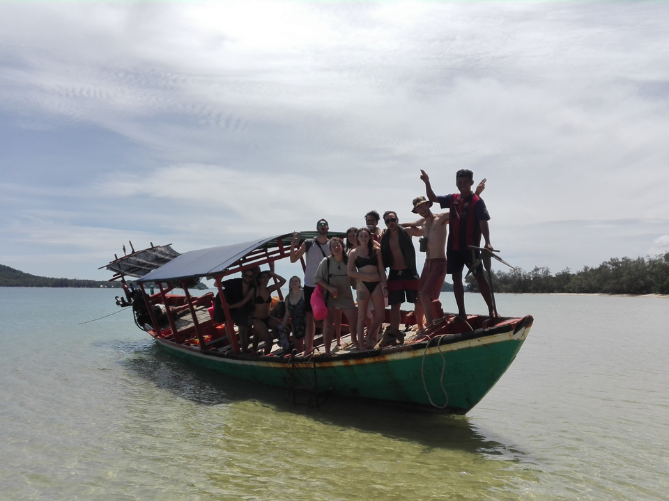 Group of people on a traditional boat at the beach.