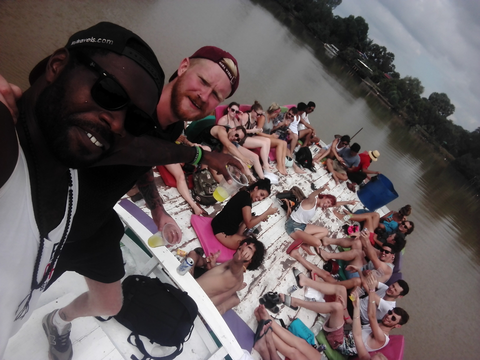 Large group relaxing on a boat on a river.