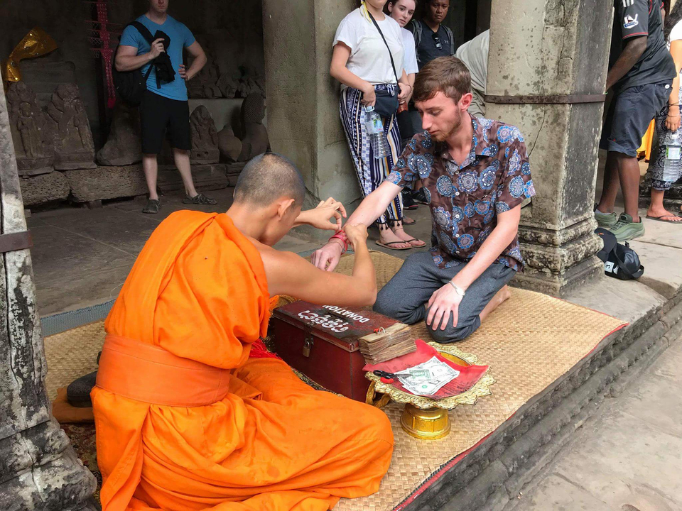 Monk tying a blessed thread on a man's wrist.