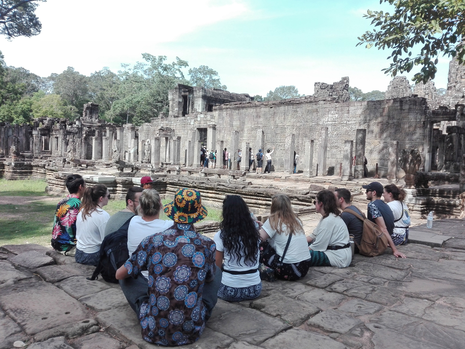 People observing dancers at ancient temple ruins.