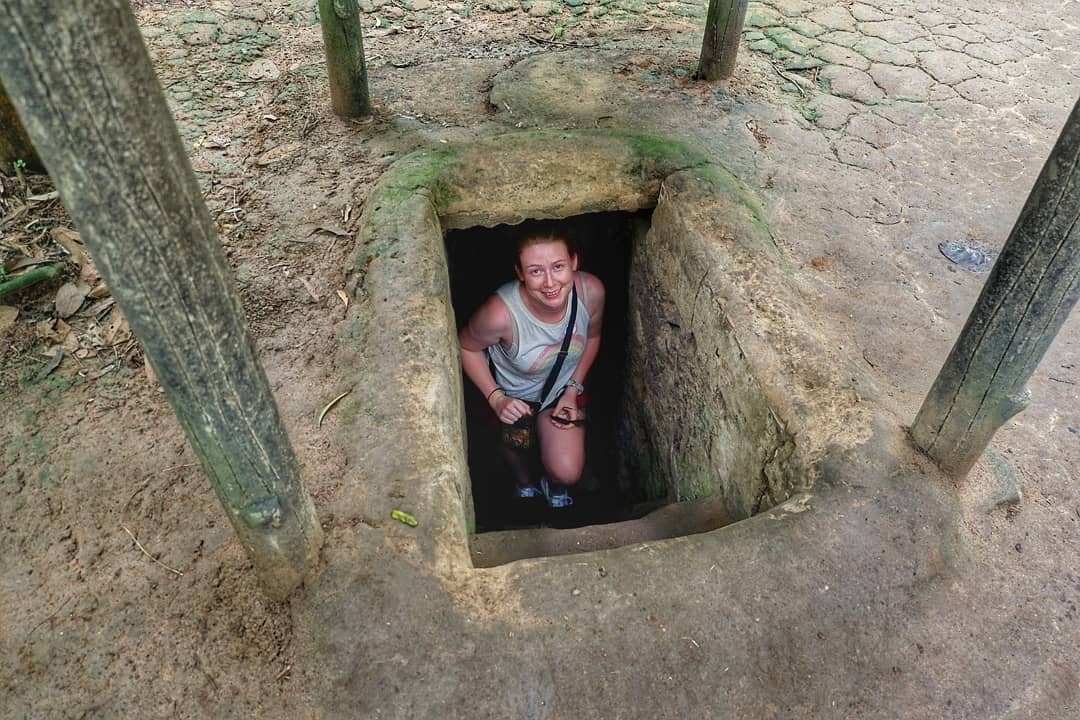 A person emerging from a small tunnel entrance.