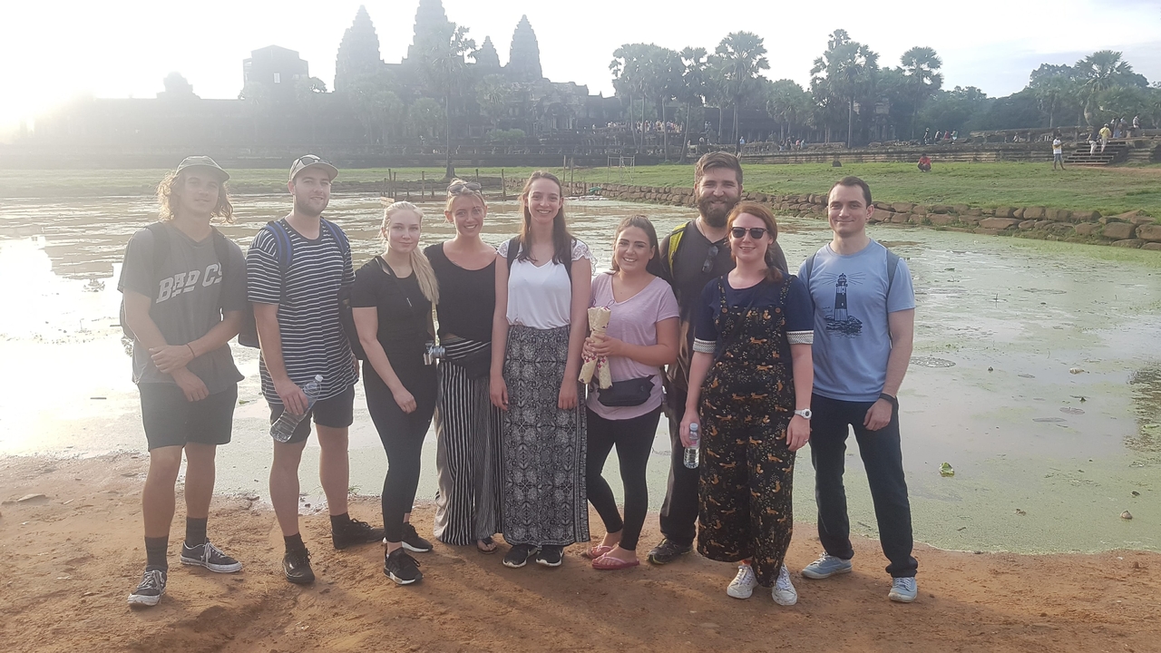 Un groupe de personnes posant devant un site historique.
