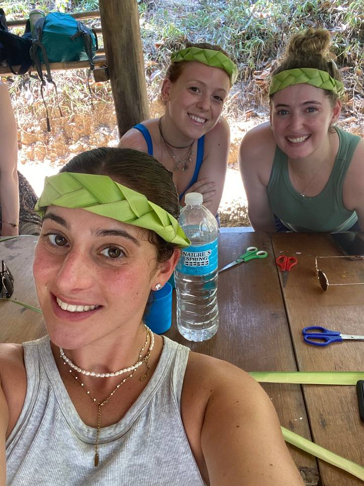Trois personnes posant avec des bandeaux de feuilles.