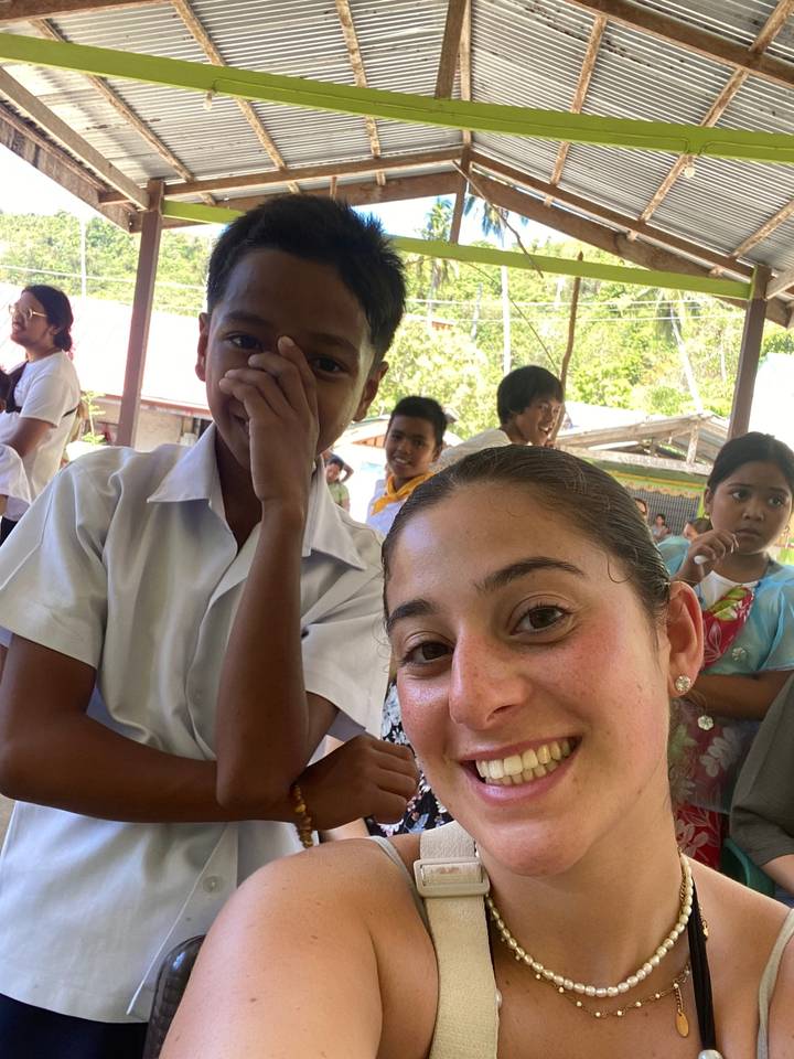 Personne souriante avec des enfants dans un cadre rural.