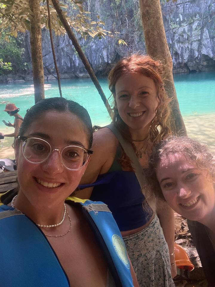 Trois personnes posant avec des arbres et de l'eau en arrière-plan.