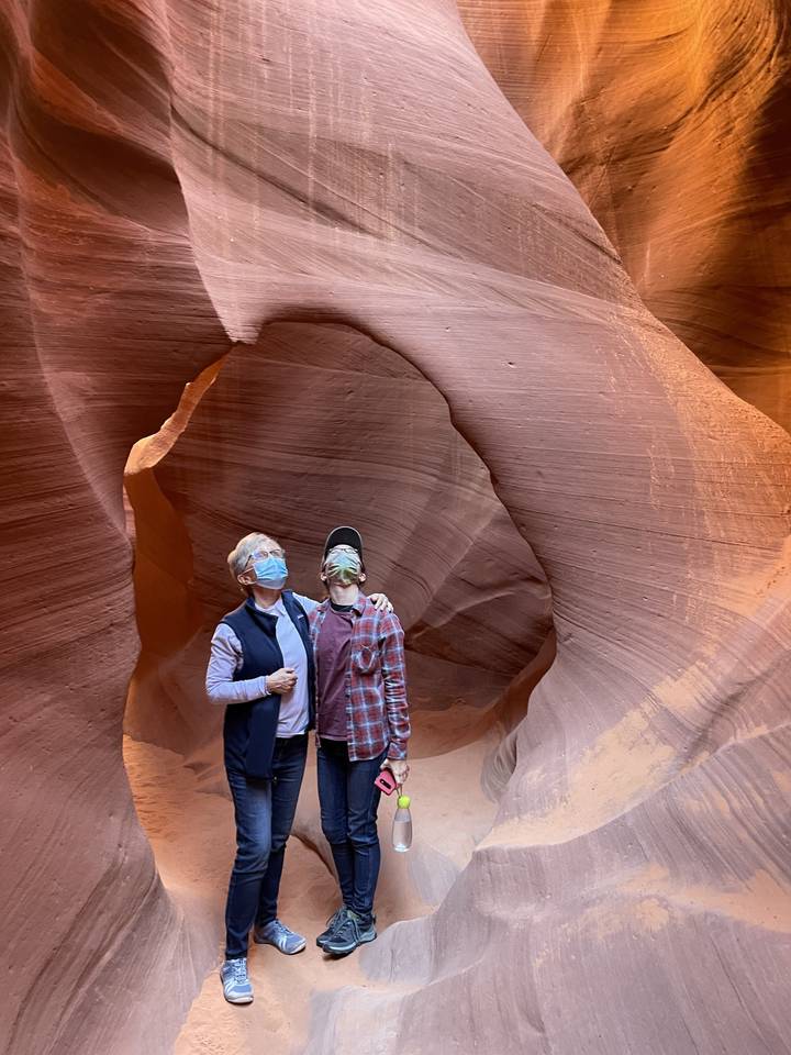 Two people standing inside a narrow canyon with facemasks.