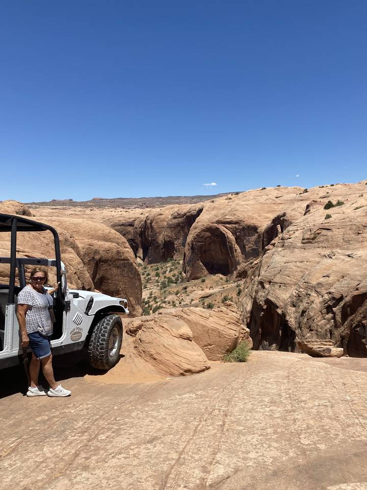 Sunlit rocky canyon landscape with a parked vehicle.