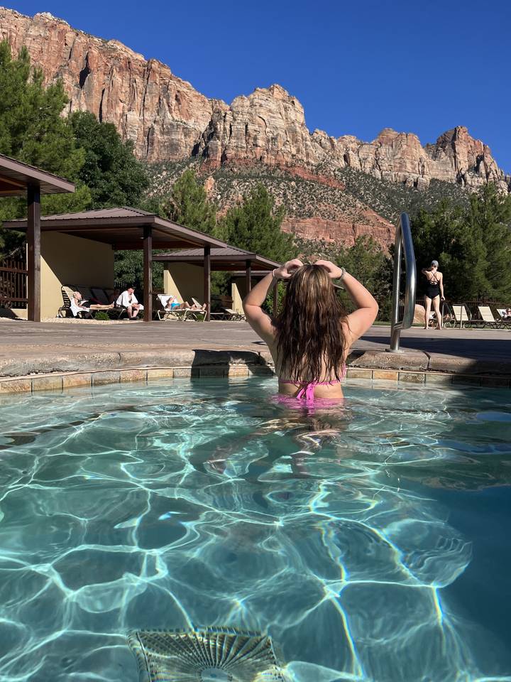 Person in a pool with mountains in the background