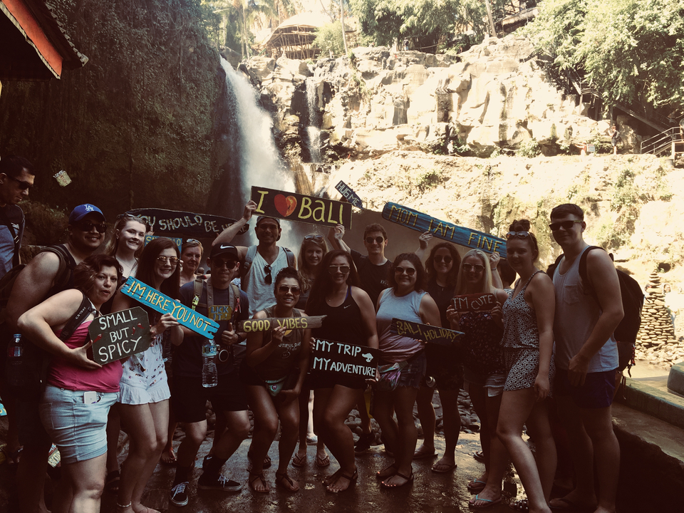 Group with signs in front of a waterfall.