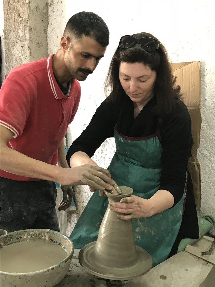 People practicing pottery with clay on a potter's wheel.