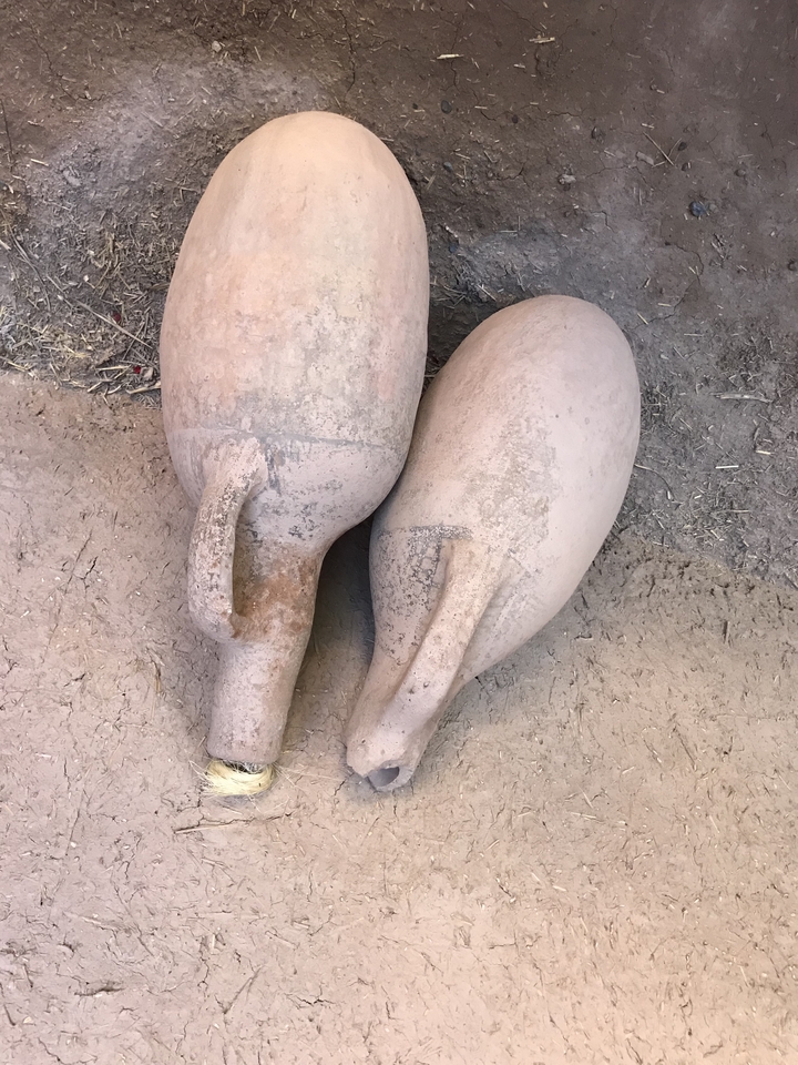 Close-up of two large clay pots on a dirt ground.