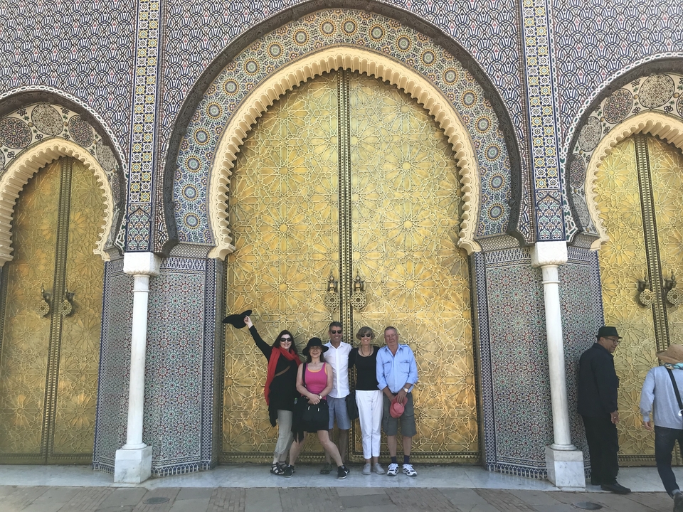 Group of people posing in front of a decorative golden door.