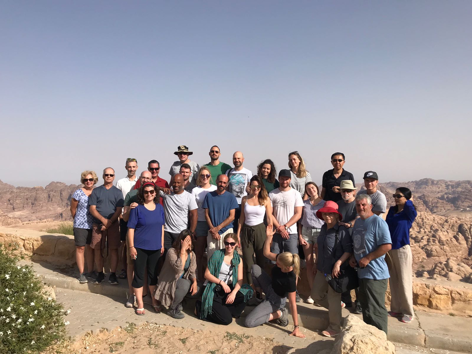 A large group of people posing against a desert landscape.