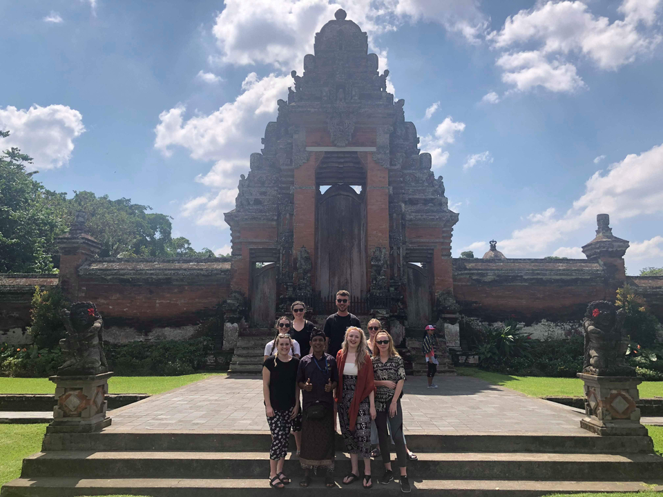 Group of tourists posing in front of a historic temple.