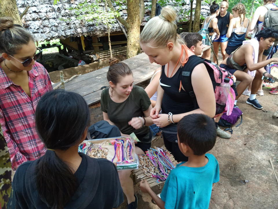 Tourists interacting with locals at a crafts market.