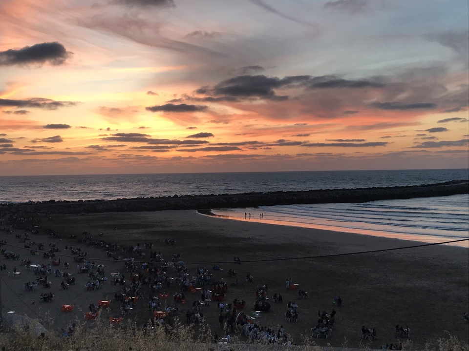 Sunset view over a beach with a gathering of people.