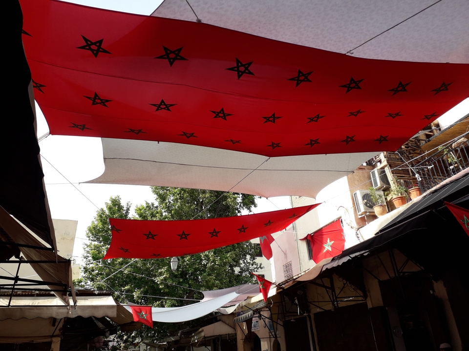 Open-air market with red banners bearing black stars.