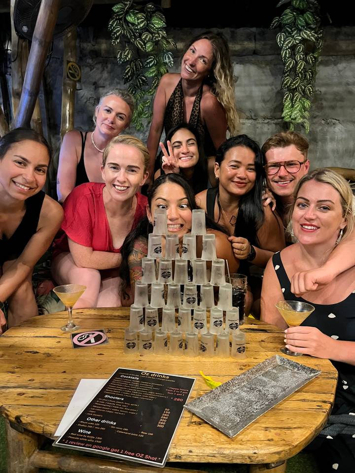 Group of people indoors with stacked shot glasses.