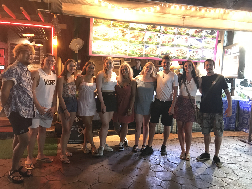 Group of people posing in front of a food stall at night.