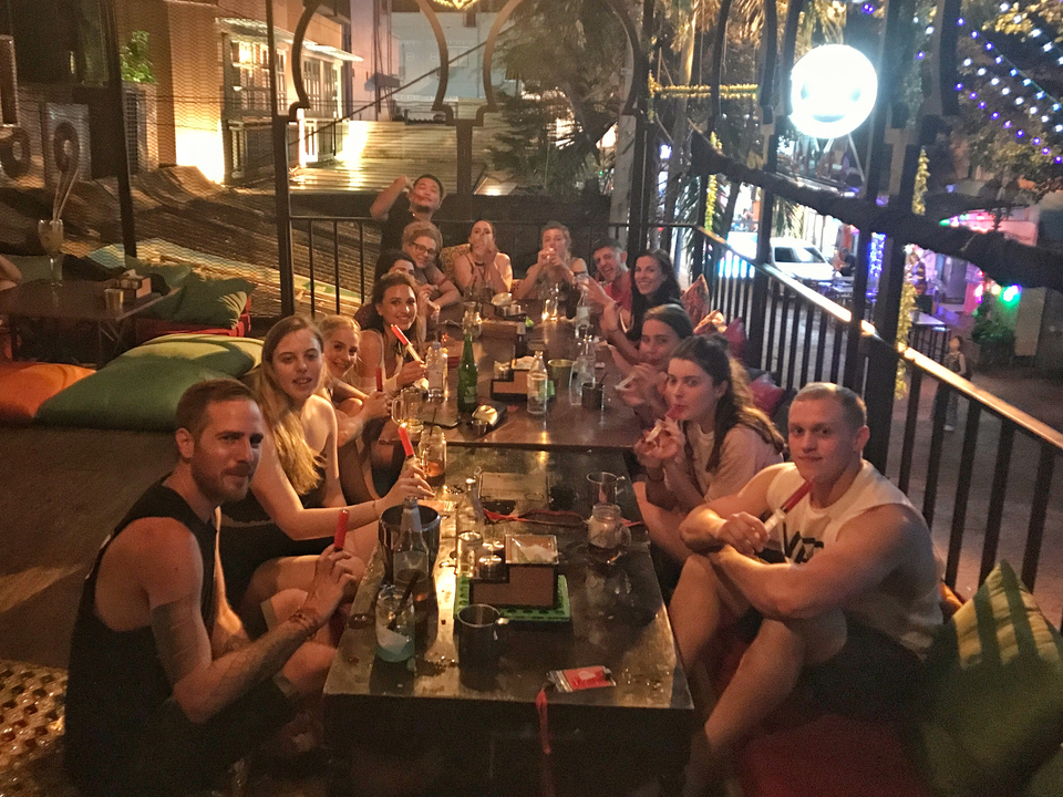Large group enjoying drinks around a table in a bar.