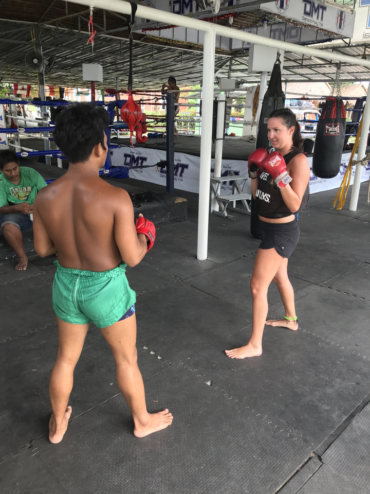 Two people engaged in a Muay Thai boxing session in a gym.