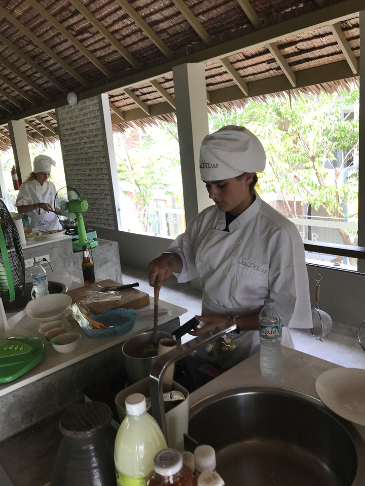A person cooking in a professional kitchen setting.